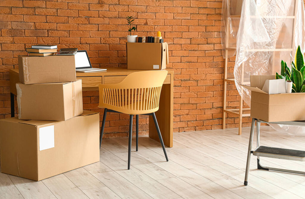 Kartondoboz tárgyakkal és bútorokkal az iroda belsejében a költözés napján - Fotó, kép