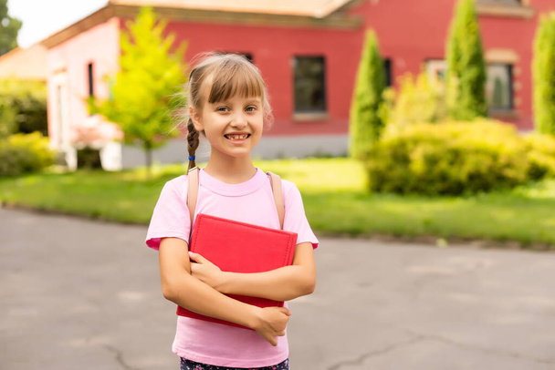 Okula dönelim. Eğitim konsepti. Okula giderken gülümseyen tatlı bir kız öğrenci. Sırt çantasıyla kitapları tutan mutlu küçük kız çocuğu.. - Fotoğraf, Görsel