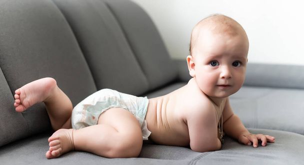 Söpö hymyilevä vauva harmaalla sohvalla - Valokuva, kuva
