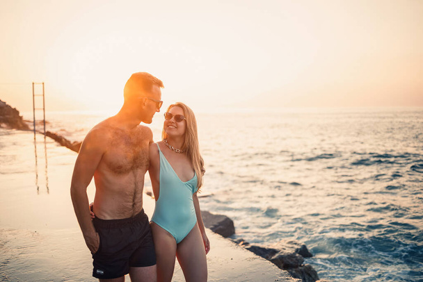 Romantyczna zakochana młoda para spacerująca razem o zachodzie słońca wzdłuż śródziemnomorskiej plaży. Wakacje w ciepłym kraju. Szczęśliwa para małżeńska na wakacjach w Turcji. Skupienie selektywne - Zdjęcie, obraz