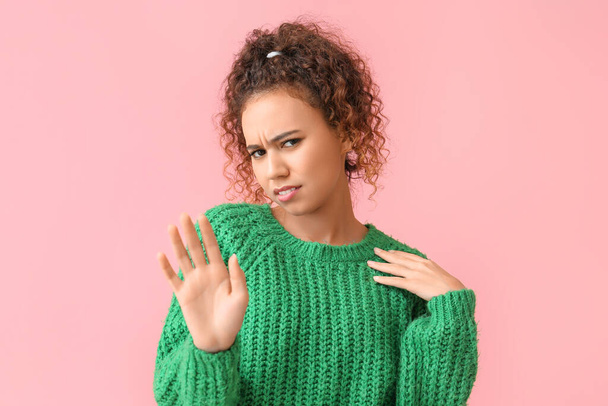 Zdenerwowana młoda Afroamerykanka w zielonym swetrze na różowym tle - Zdjęcie, obraz