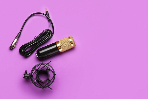 Moderne microfoon met standaard en draad op paarse achtergrond - Foto, afbeelding