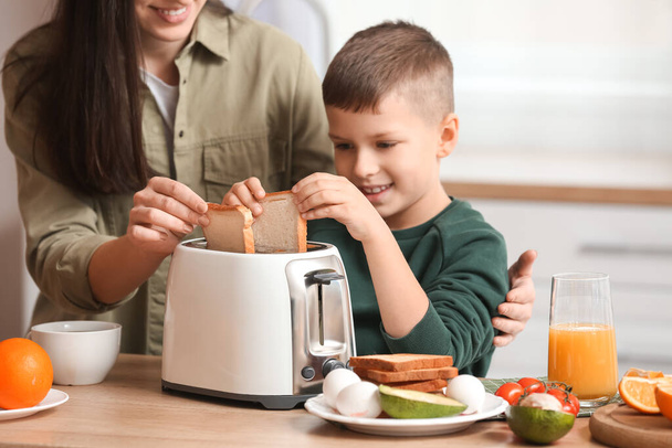 Piccolo ragazzo con sua madre fare gustosi toast in cucina - Foto, immagini