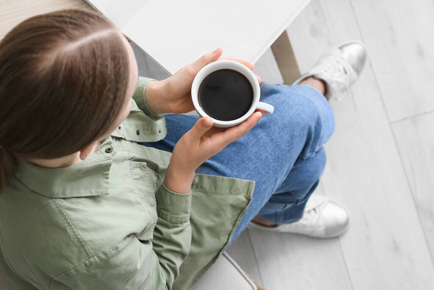 Jeune femme avec tasse de café chaud dans la cuisine, gros plan - Photo, image