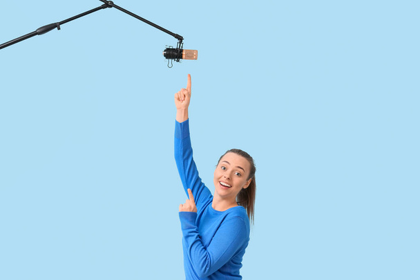 Giovane donna che punta al microfono professionale su sfondo blu - Foto, immagini
