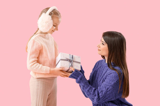Šťastná matka dává své malé dceři dárek na růžovém pozadí - Fotografie, Obrázek