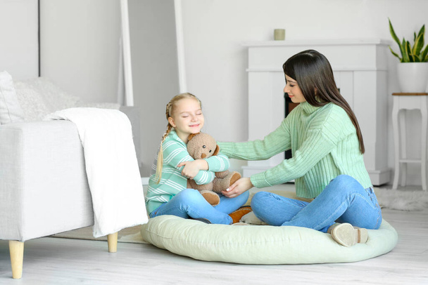 gelukkig klein meisje en haar moeder in warm truien met speelgoed thuis - Foto, afbeelding