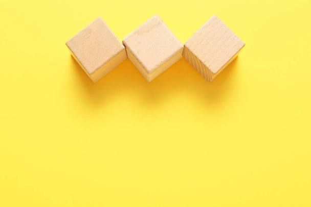 Wooden cubes on yellow background - Foto, afbeelding