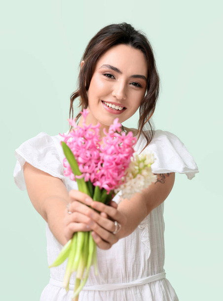 Pretty young woman with hyacinth flowers on green background - Photo, image