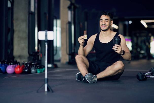 Schöner arabischer männlicher Athlet wirbt in seinem Videoblog mit Fitness-Snacks - Foto, Bild