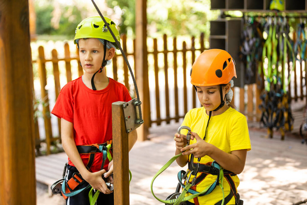 Roztomilé děti. Chlapec a dívka lezení v laně hřiště struktury v dobrodružném parku - Fotografie, Obrázek