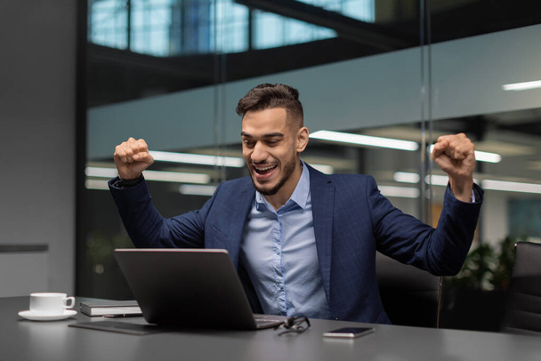 Συναισθηματικός αραβικός επιχειρηματίας γιορτάζει την επιτυχία στο γραφείο - Φωτογραφία, εικόνα