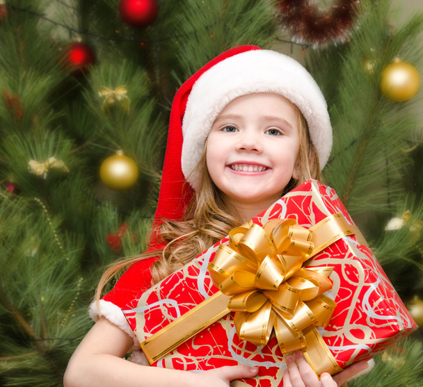 Cute smiling little girl in santa hat with gift box - Fotoğraf, Görsel