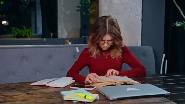 Una giovane, triste studentessa, sopraffatta dai compiti, si siede con un portatile in un caffè. - Filmati, video