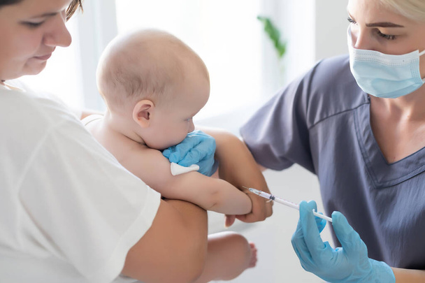 Pediatrician doctor with syringe, tense mother and baby - Valokuva, kuva