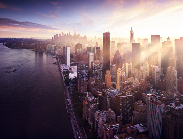 New York City - piękny kolorowy zachód słońca nad manhattan pasuje promienie słońca między budynkami - Zdjęcie, obraz