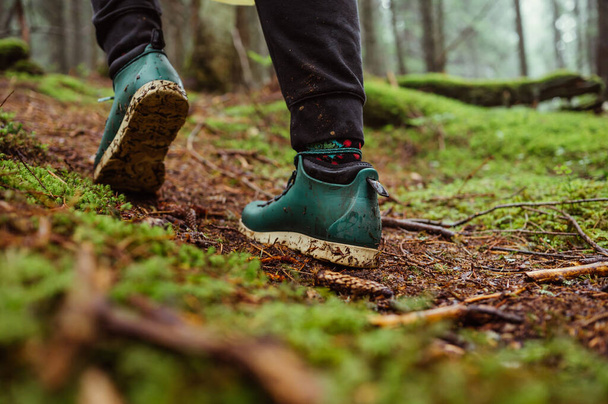 Πόδια στα παπούτσια ενός τουρίστα περπατούν στο έδαφος με τα βρύα του τροπικού δάσους - Φωτογραφία, εικόνα