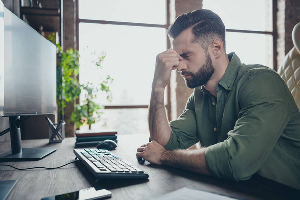 Profile side view portrait of attractive tired guy writing solving task developing project touching nose at work place station indoors - Фото, изображение
