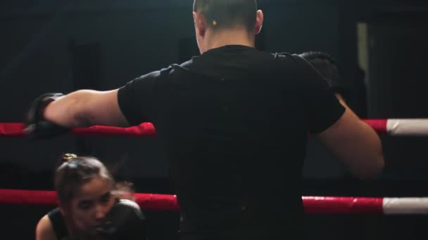 Nuori nainen harjoittelee väistelyä urospuolisen kouluttajansa kanssa nyrkkeilykehässä - Materiaali, video