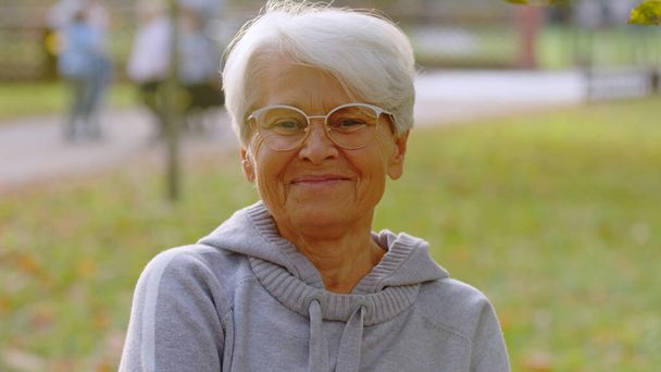 Portret van oudere blanke vrouw grijs haar en bril in het park selectieve focus  - Foto, afbeelding