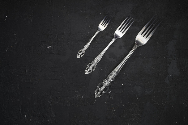 Overhead shot of silverware on black table with copy space. - Photo, image