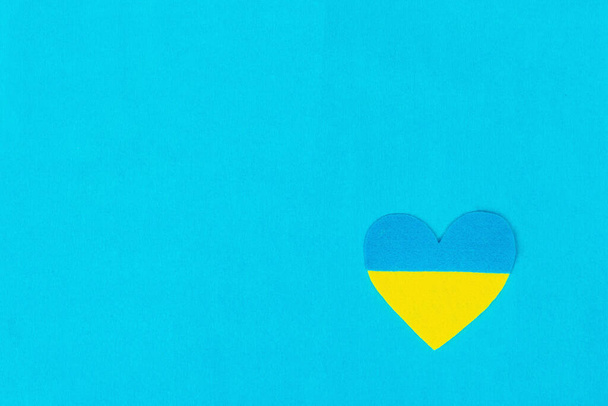 Heart in the colors of the Ukrainian flag. Stop the war concept. The heart from felt on blue background. Flat lay, a place for text, mockup, template, top view - Foto, imagen