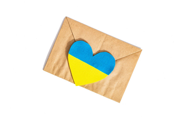 Конверт и сердце в цветах украинского флага. Остановить войну концепции изолированы на белом фоне. Плоская постель, место для текста, макета, искушения, вид сверху - Фото, изображение