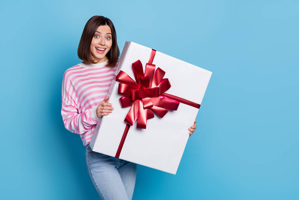 Photo of impressed millennial brunette lady hold large present wear pink jumper isolated on blue background - Foto, afbeelding