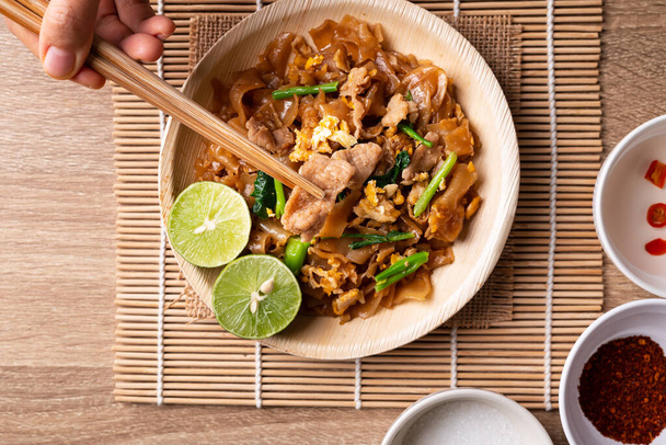 Comida tailandesa (Pad See Ew), Mexa macarrão de arroz frito com molho de soja, ovo, couve e carne de porco comendo por uso de pauzinhos, Vista superior da mesa - Foto, Imagem