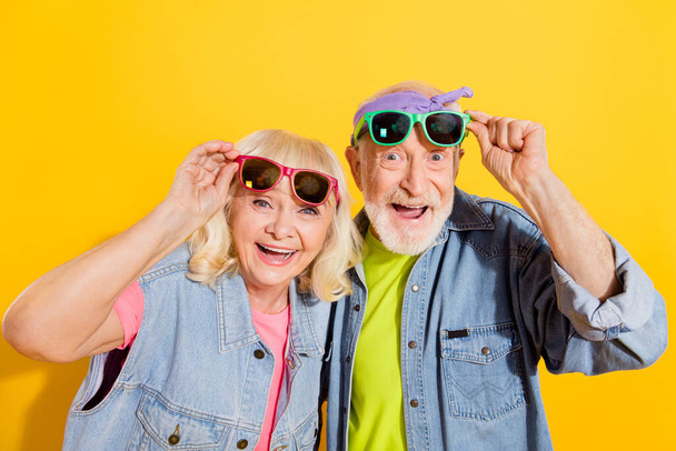 Portrait of attractive amazed cheerful grey-haired family touching specs having fun isolated over bright yellow color background - Fotoğraf, Görsel