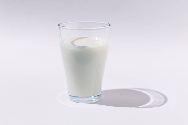 Full glass glass of milk in hard light on WHITE background. Dairy, shortage, calcium, grow and drink concept - Foto, imagen