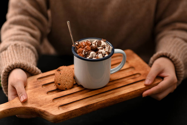 Close-up, Woman hands holding a wooden plate with a cup of hot chocolate, marshmallow and cookies. - Photo, Image
