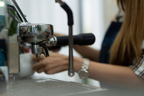 Joven barista haciendo espresso con cafetera profesional Joven mujer preparando café usando la máquina en la cafetería - Foto, imagen