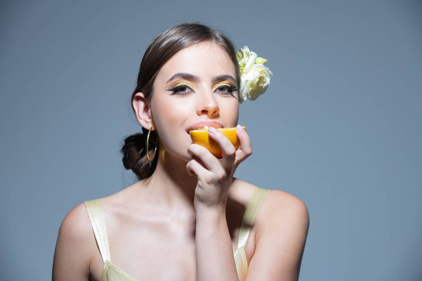 Sexy summer tropical fruit. Young beautiful model eating orange in studio. Summer mood. Dreaming italian or hispanic girl. - Photo, Image