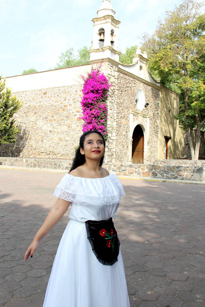 Junge Teenagerin trägt ein weißes mexikanisches Regionalkleid mit schwarz bestickten Details, das traditionell aus dem Bundesstaat Veracruz Mexiko stammt und stolz auf ihre tanzbereite Kultur ist - Foto, Bild