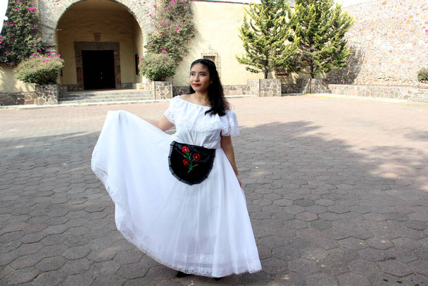 Young teenager woman wears a white regional Mexican dress with black embroidered detail traditional from the state of Veracruz Mexico proud of her culture ready to dance - Photo, Image