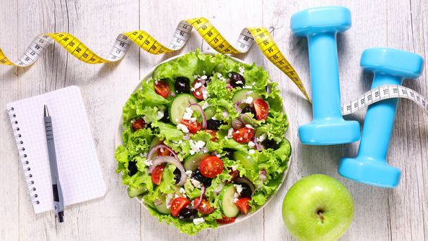 diet food concept- salad with dumbbell and meter - Foto, Imagen