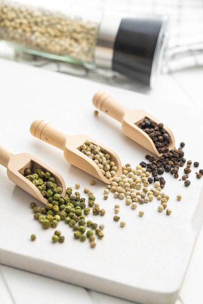 Three different types of pepper spice. Green, white and black peppercorn in the wooden scoops. - Foto, Imagem