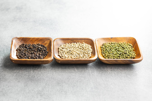 Three different types of pepper spice. Green, white and black peppercorn in the bowls. - Foto, afbeelding