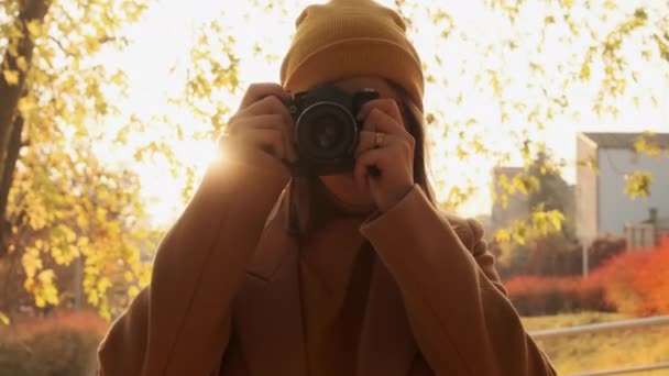 A kamera egy fiatal fényképész körül forog, aki naplementekor fényképez egy őszi parkban. - Felvétel, videó