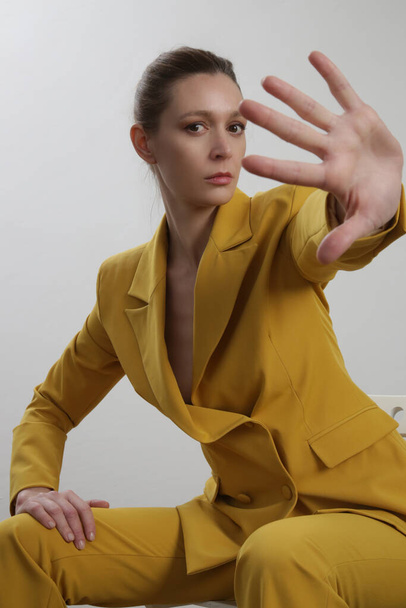 Γυναικείο μοντέλο με κίτρινο κοστούμι. Φωτογραφία στούντιο. - Φωτογραφία, εικόνα