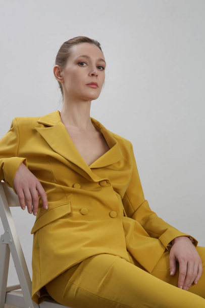 Modèle féminin portant un costume jaune sur mesure. Plan studio. - Photo, image