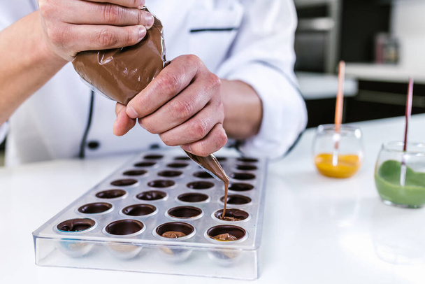 Latinalainen mies kondiittori yllään yhtenäinen parhaillaan valmistaa herkullisia makeisia suklaata keittiössä Meksikossa Latinalaisessa Amerikassa - Valokuva, kuva