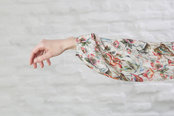 Braço da mulher em blusa de seda floral, imagem interior aganst parede branca - Foto, Imagem