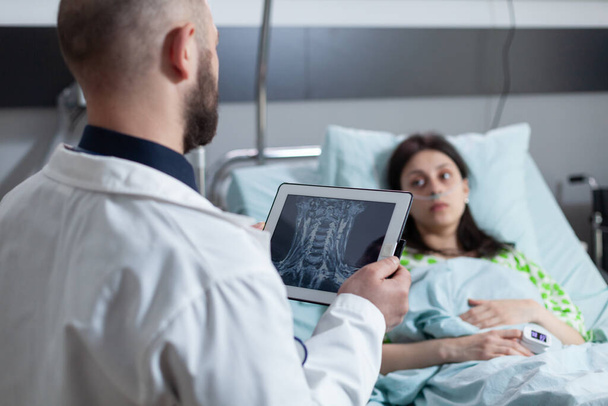 Arts die digitale tablet met MRI scan van keel gebied lezen diagnose aan betrokken patiënt - Foto, afbeelding
