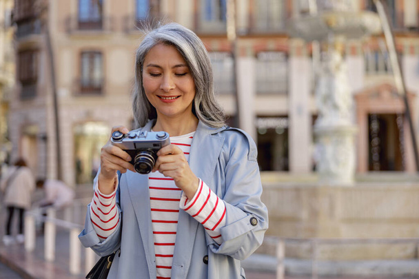 Веселая женщина-фотограф прогуливается по центру города - Фото, изображение