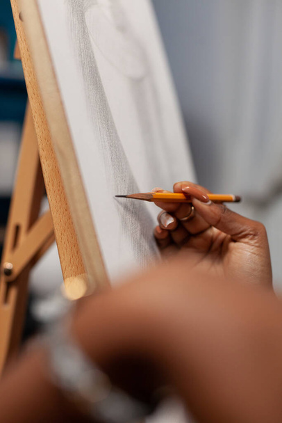 Gros plan de la main d'un jeune artiste étudiant tenant un crayon graphique - Photo, image
