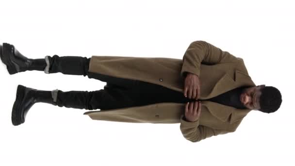 joven enérgico macho ajustando su abrigo y clasificándolo, vertical, fondo blanco - Metraje, vídeo