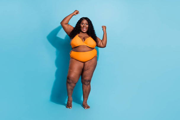 Full length portrait of curvy figure obesity lady raise fists achieve luck enjoy herself no filters isolated on blue color background - Fotografie, Obrázek