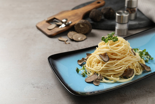 Delicious pasta with truffle slices and microgreens served on light grey table, space for text - Фото, изображение